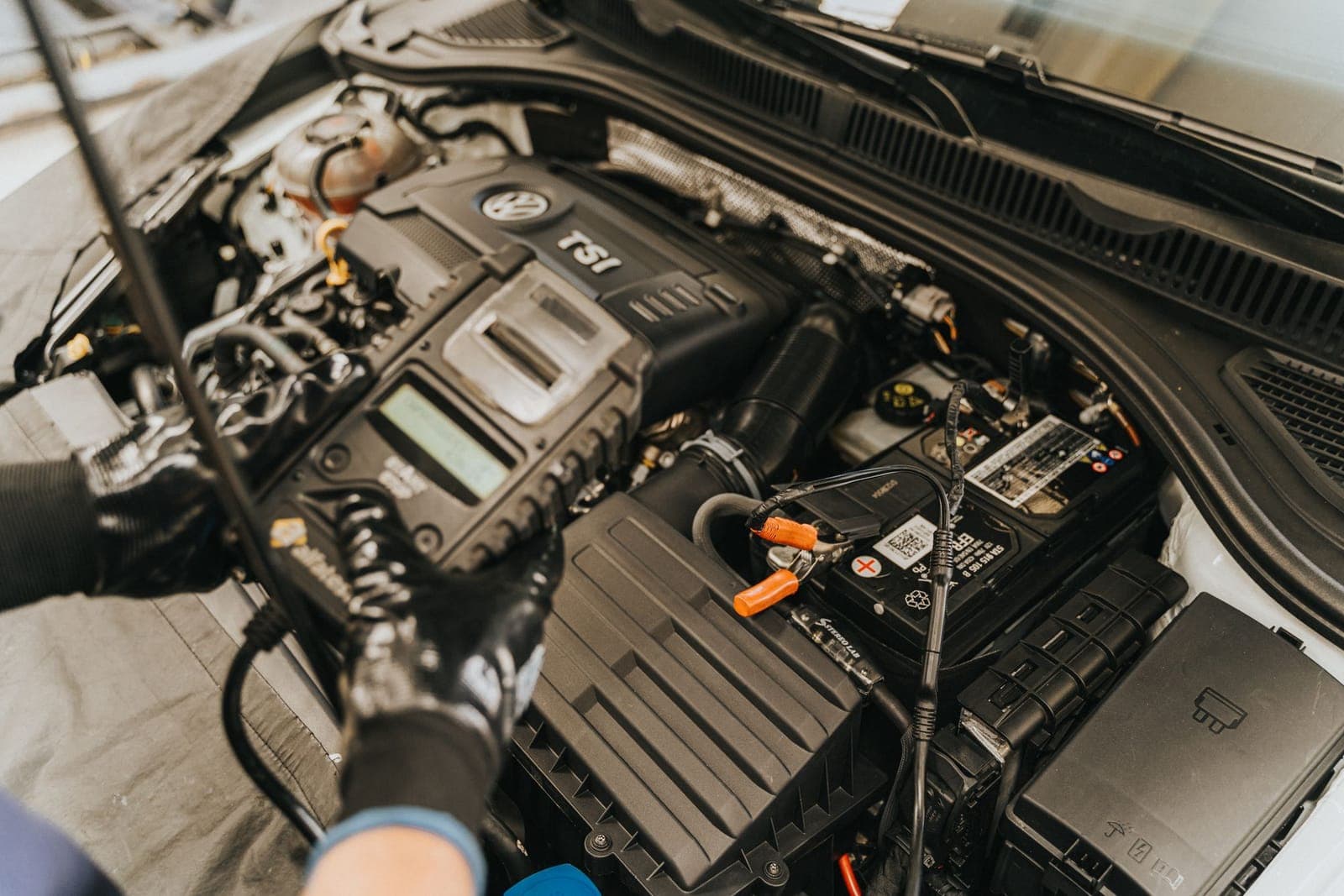 Outil de diagnostic posé sur un moteur essence, capot ouvert