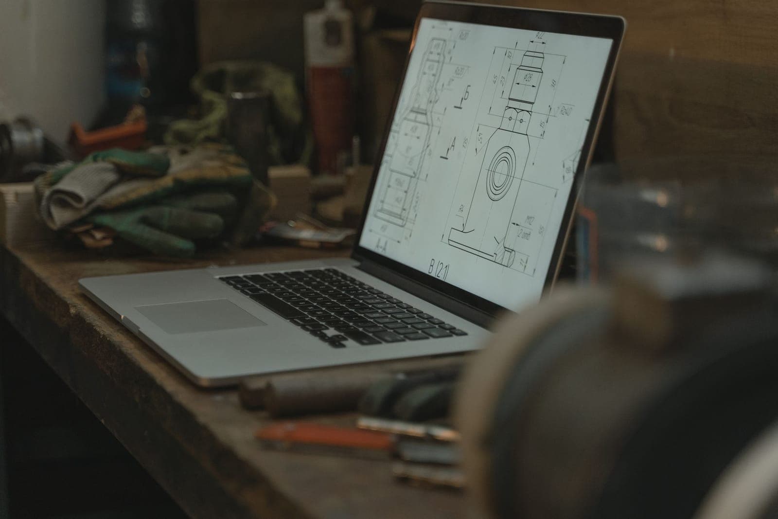 Ordinateur portable ouvert sur un établi d'atelier, entouré d'outils